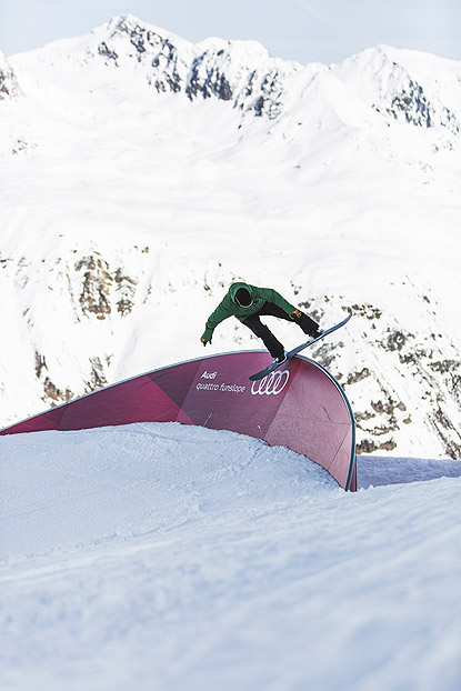 Snowboarder slided über ein Obstacle mit Audi Brand