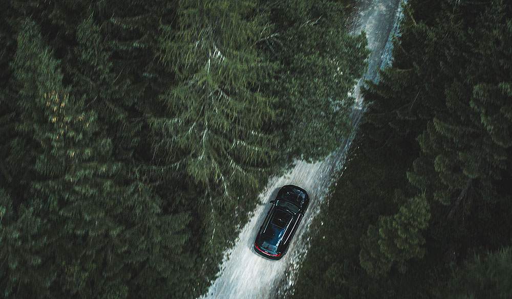 Schwarzer Audi e-tron fährt durch einen Wald und wird von oben fotografiert