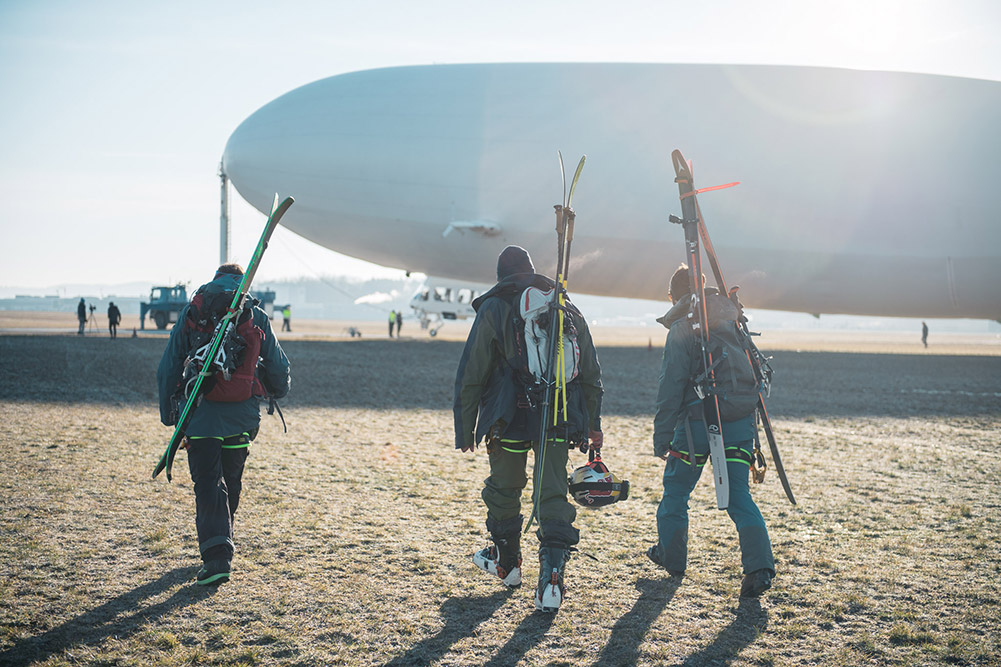 Drei Menschen vor einem Zeppelin